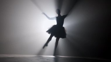 Sahne ışıkları altında dans eden profesyonel balerin büyük sahnede sigara içiyor..