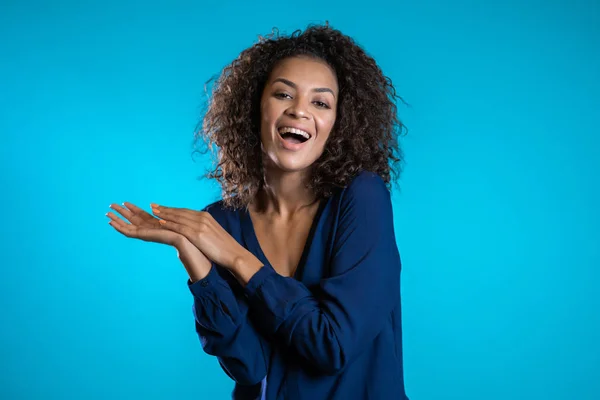 Attraktiv afrikansk amerikansk kvinna med afro hår i affärskläder ler mot kameran över blå vägg bakgrund. Söt blandras flickor porträtt — Stockfoto