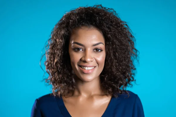 Mulher americana africana atraente com cabelo afro em roupas de negócios sorrindo para câmera sobre fundo de parede azul. bonito misto raça meninas retrato — Fotografia de Stock