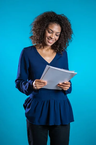 꽤 나많은 아프리카 계 미국인 여성 보스가 서류, 공과금을 확인 합니다. 심각 한 사업가가 푸른 배경 위에 서 있습니다. 그녀는 직원들의 일에 만족 합니다. — 스톡 사진