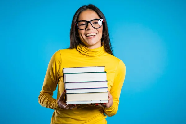 Λατίνος φοιτητής σε μπλε φόντο στο στούντιο κατέχει στοίβα από πανεπιστημιακά βιβλία από τη βιβλιοθήκη. Ο τύπος χαμογελάει, χαίρεται που αποφοιτά.. — Φωτογραφία Αρχείου