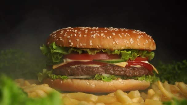 Grote smakelijke hamburger met vleessnijder, ui, groenten, gesmolten kaas, sla — Stockvideo