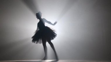 Sahne ışıkları altında dans eden profesyonel balerin büyük sahnede sigara içiyor..