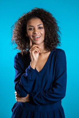 Afro saçlı, iş kıyafetleri içinde gülümseyen çekici Afrikalı Amerikalı kadın. 