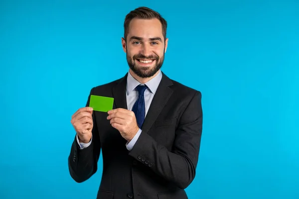 Sikeres férfi öltönyben, korlátlan zöld hitelkártyával, kék stúdió háttérrel. Szakmai férfi menedzser. — Stock Fotó