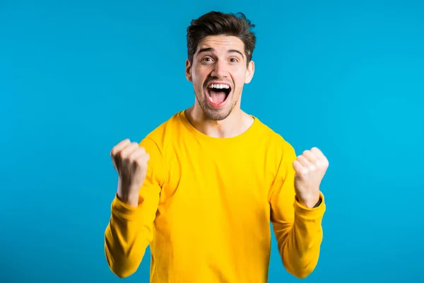 Yes winner gesture. Happy european man. Handsome guy with stylish hairdo surprised to camera over blue background — Stock Photo, Image