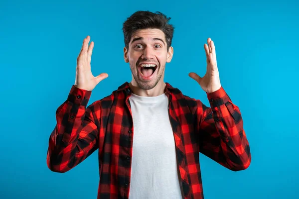 Der glückliche Europäer freut sich. schöner Kerl mit stylischer Frisur überrascht vor der Kamera vor blauem Hintergrund. — Stockfoto