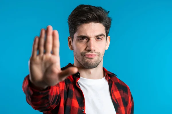 No, never, handsome brunette man disliking and rejecting gesture by stop sign. Portrait of young successful confident guy isolated on blue background — Stock Photo, Image