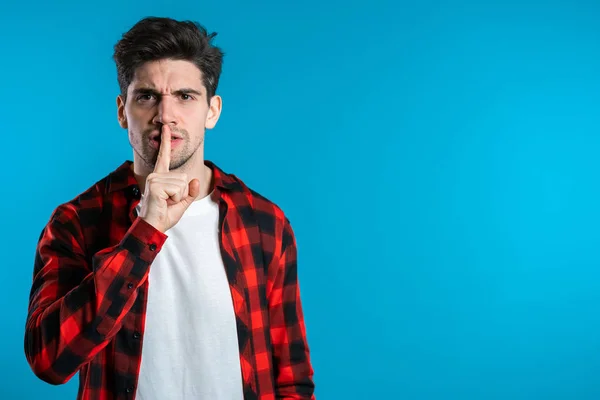 European handsome man holding finger on his lips over blue background. Gesture of shhh, secret, silence — Stock Photo, Image