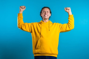 Evet, kazanan jest. Mutlu Avrupalı adam. Şık saçlı yakışıklı adam mavi arka planda kameraya şaşırdı.