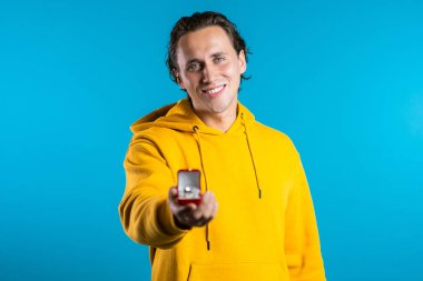 Genç yakışıklı adam kameraya alyanslı mücevher kutusunu uzatıyor. Adam evlilik teklifi yapıyor. Gülümsüyor..