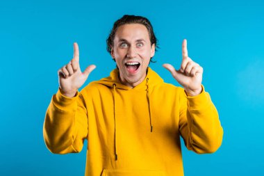 Sarı elbiseli genç düşünceli adamın portresi mavi stüdyonun arka planında bir fikir belirtiyor. Gülümseyen mutlu öğrenci, Eureka hareketi yapıyor..