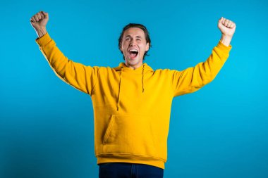 Evet, kazanan jest. Mutlu Avrupalı adam. Şık saçlı yakışıklı adam mavi arka planda kameraya şaşırdı.