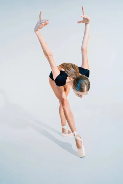Professionele ballerina dansen ballet op witte Cyclorama. Mooi jong meisje met lang haar dragen zwarte pak geïsoleerd op witte studio achtergrond. — Stockfoto