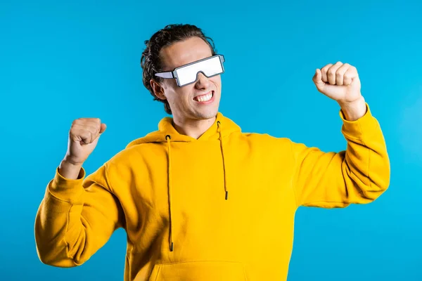 Világító szemüveges hipszteres férfi, aki a zene ritmusára mozog a kék stúdió hátterében. Táncoló pozitív képregény srác — Stock Fotó