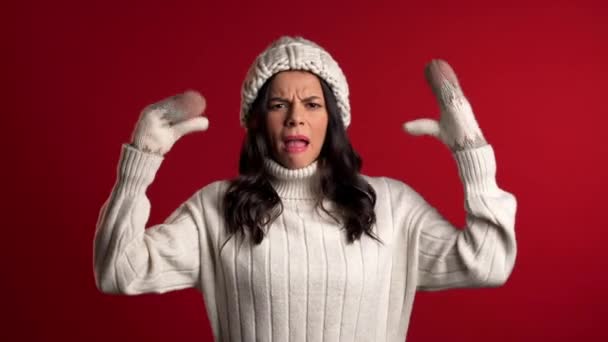 Attractive bored woman in white sweater showing bla-bla-bla gesture with hands and rolling eyes isolated on red background. Empty promises, blah concept. Lier. — Stock Video