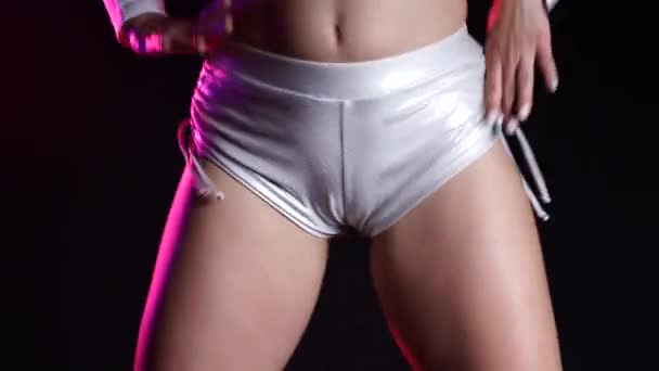 Mujer sexy en pantalones cortos de plata bailando danza moderna twerk. Chica temblando, twerking sus nalgas de cerca sobre fondo negro, luz de neón . — Vídeo de stock