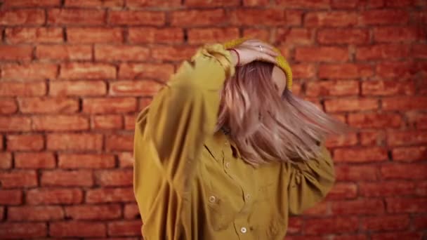 Mujer inusual con pelo rosa divirtiéndose, sonriendo, bailando con la cabeza en el estudio sobre fondo de ladrillos. Música, concepto de danza, cámara lenta — Vídeos de Stock