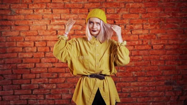 Attraente donna insolita con i capelli rosa in giallo mostrando bla-bla-bla gesto con le mani e gli occhi rotolanti isolati su sfondo mattoni. Promesse vuote, bla-concetto. Lier. — Video Stock