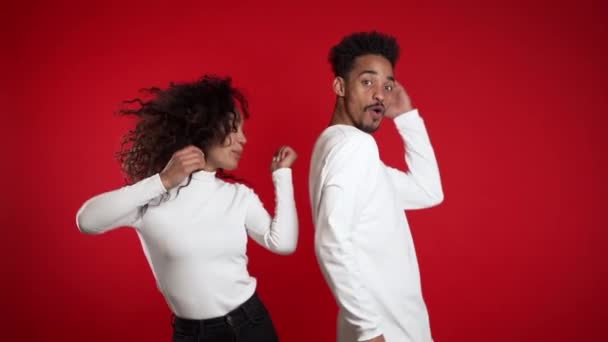 Jeune couple afro-américain dansant isolé sur fond rouge studio. Fête, bonheur, concept de musique . — Video