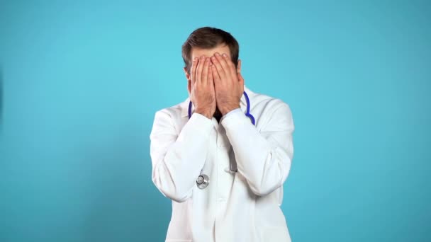 Jonge arts in professionele medische witte jas bedekt zijn gezicht met handen van fatale teleurstelling, mislukking. Depressieve verloren man. Drama, emotie concept. — Stockvideo