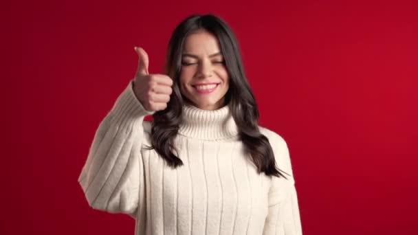 Jonge latijnse vrouw met perfecte make-up maken duimen omhoog teken over rode achtergrond. Winnaar. Succes. Positief meisje lacht naar de camera. Lichaamstaal. — Stockvideo