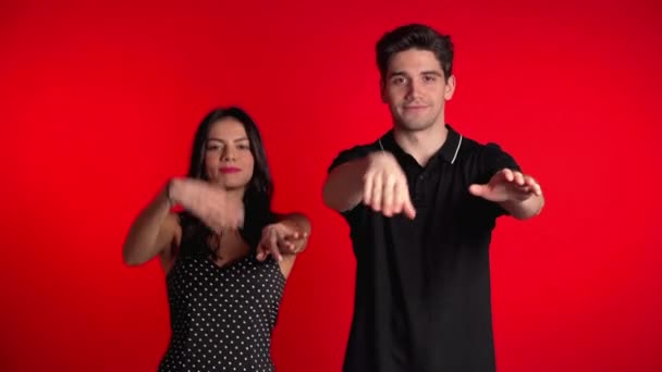 Junges Paar tanzt lustigen Meme-Tanz auf rotem Studiohintergrund. Liebe, Urlaub, Glückskonzept. — Stockvideo
