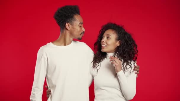 Retrato de una joven pareja afroamericana sobre fondo de estudio rojo. Amor, vacaciones, concepto de felicidad . — Vídeo de stock