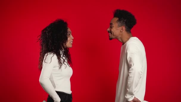 若いアフリカ系アメリカ人のカップルは、赤いスタジオの背景で贈り物を交換します。愛、休日、幸福の概念. — ストック動画