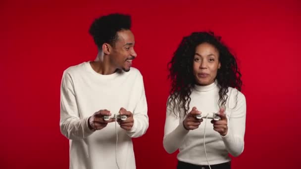 Pretty young african match playing video exciting game on Tv with joystick on red studio wall. Using modern technology. — 비디오