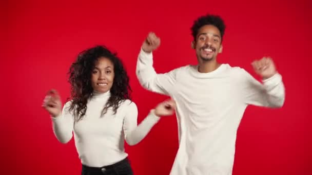 Giovane coppia afroamericana che balla isolata su uno studio di sfondo rosso. Festa, felicità, concetto di musica. 4k . — Video Stock