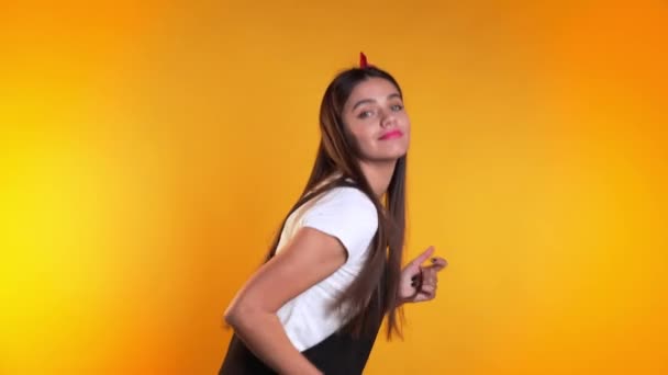 Chica bonita joven en vestido sonriendo y bailando en excelente estado de ánimo sobre fondo amarillo. Felicidad, concepto de fiesta . — Vídeo de stock