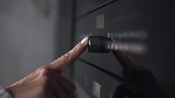 Female finger presses a button on modern gas stove or oven. Woman cooking dinner in modern kitchen with equipment. Closeup view. — Stockvideo