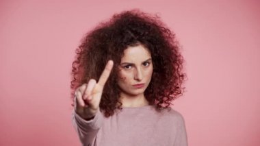 Çapraz el işareti olmadan onaylamayan güzel bir kız inkar jesti yapar. Reddetmek, reddetmek, anlaşmazlık, pembe arka planda kadın portresi.