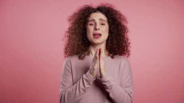 Pembe arka plan için dua eden sevimli Avrupalı genç kız. Birine yalvaran bir kadın. 4k.