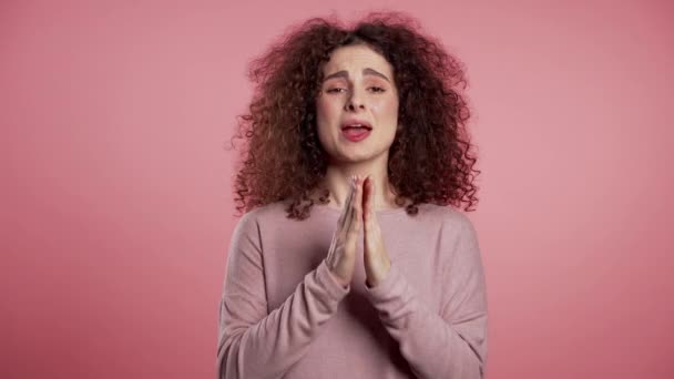 Słodka młoda Europejka modli się o różowe tło. Kobieta błagająca kogoś. 4k. — Wideo stockowe