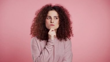 Pembe arka planda yukarı doğru bakan bir kadın. Dalgın yüz ifadeleri için endişelenmiş. Güzel kıvırcık kız modeli