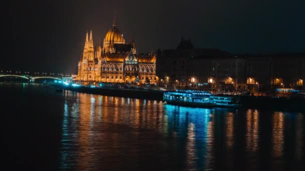 Macaristan 'ın Budapeşte kentinde Tuna ve Macaristan Parlamentosu' nda panorama gece görüşü. Eski mimari ve nehir teknelerinin aydınlatıldığı güzel bir gece ya da akşam manzarası. 4k — Stok video