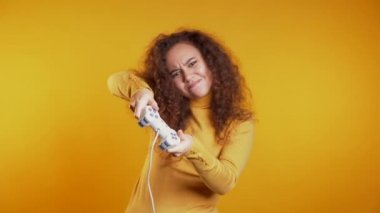 TV 'de video oyunu oynayan genç ve güzel bir kız. Stüdyonun duvarında kumanda kolu var. Modern teknolojiyi kullanarak.