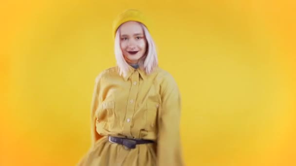 Mooie vrouw met roze haar en piercing dansende meme dans op kleurrijke gele studio achtergrond. Schattig meisjes portret. Feest, geluk, vrijheid, jeugdconcept. — Stockvideo
