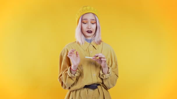 Pretty unusual girl breaking the last cigarette isolated on yellow background. Quit smoking, bad habit concept. — Stock Video