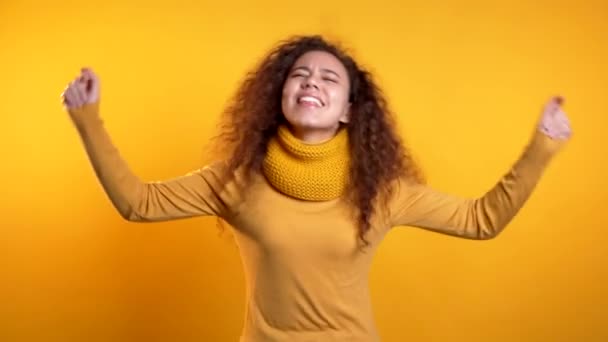 Mooie vrouw met krullend haar dansend op kleurrijke gele studio achtergrond. Schattig meisjes portret. Feest, geluk, vrijheid, jeugdconcept. — Stockvideo