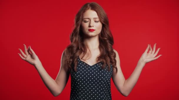 Chica positiva relajándose, meditando. La mujer se calma, respira profundamente con mudra om sobre fondo rojo del estudio. Retrato de mujer joven . — Vídeo de stock