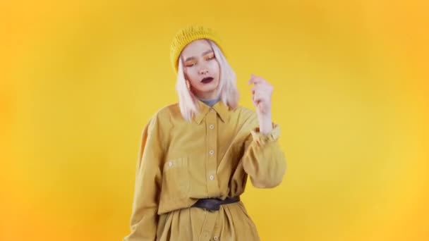 Mooie vrouw met roze haar en piercing dansen en knipt vingers op kleurrijke gele studio achtergrond. Schattig meisjes portret. Feest, geluk, vrijheid, jeugdconcept. — Stockvideo