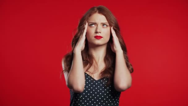 Молодая расстроенная женщина с рыжими волосами с головной болью, студийный портрет. Девушка кладет руки на голову, изолирована на красочном фоне. Концепция проблем и головной боли . — стоковое видео