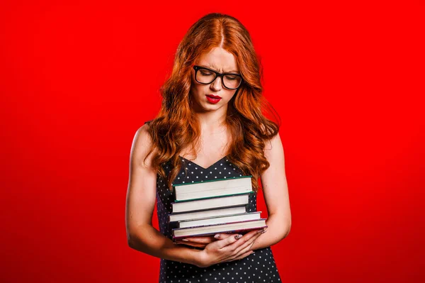 European student is dissatisfied with amount of homework. Girl with books, she is annoyed, discouraged frustrated by studies on red background in studio — 스톡 사진