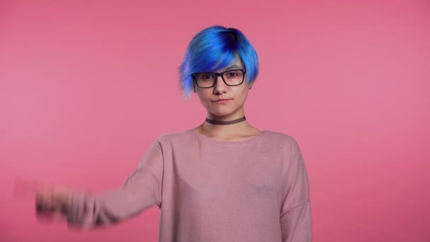 Young unusual woman with blue hair making disapproving with no finger sign, negation gesture over pink studio background — Stockvideo