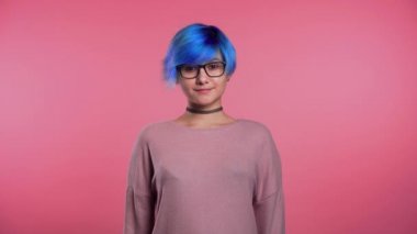 Portrait of young punk unusual woman with blue hair on pink background. Girl in transparent glasses with black choker.