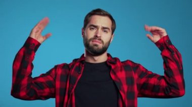 Sakallı yakışıklı bir adam. Mavi arka planda elleri ve yuvarlanan gözleriyle jest yapıyor. Boş vaatler, falan filan. Yalancı..