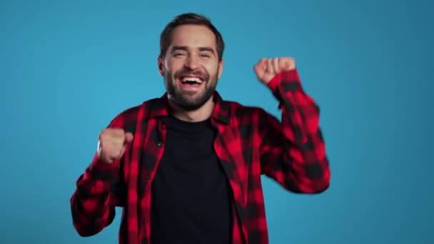 Homem com barba se divertindo, sorrindo, dançando em estúdio contra fundo azul. Música, conceito de dança — Vídeo de Stock